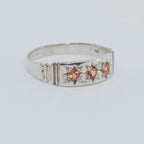 Silver ring with star-shaped gemstones on a light gray background