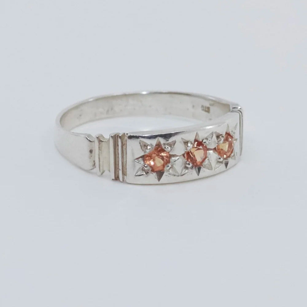 Silver ring with star-shaped gemstones on a light gray background