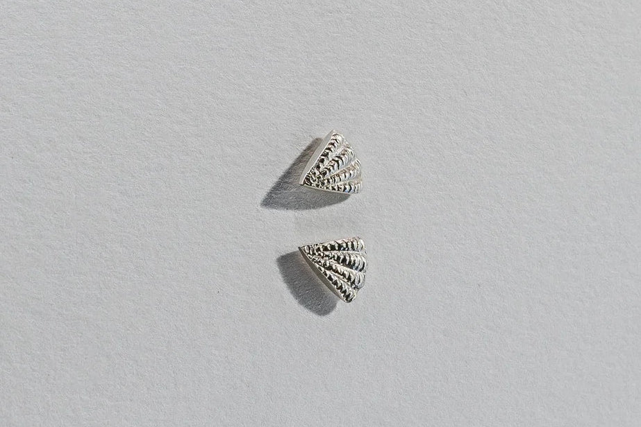 Pair of silver shell-shaped earrings on a light gray background